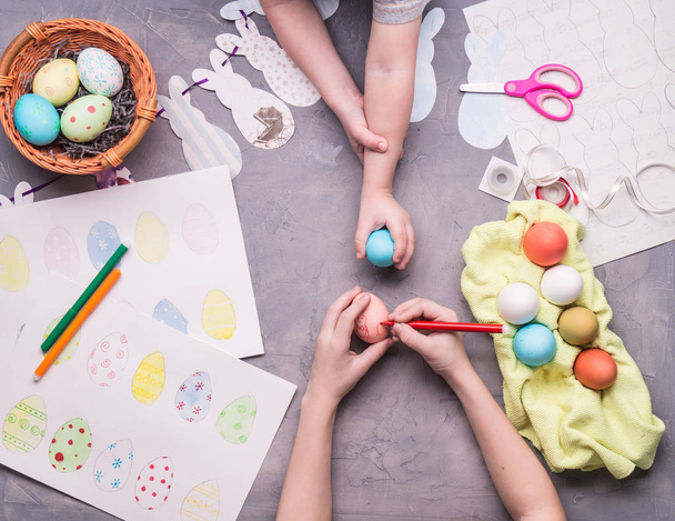 Preparing for the celebration of Easter: the girl makes a drawing on the Easter egg. - Valokuva, kuva