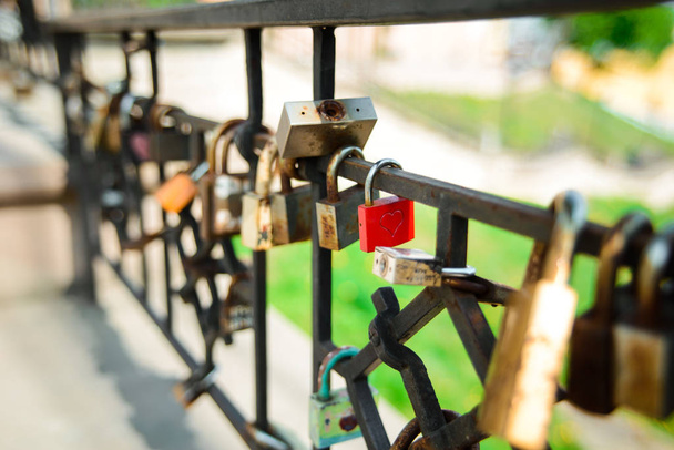 Cerradura de hierro rojo con corazón tallado cuelga en una barandilla de puente que simboliza el amor verdadero
 - Foto, imagen