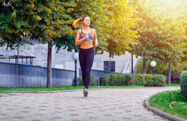 Красивая спортивная женщина бегает в парке в спортивной одежде. День тренировочного солнца
 - Фото, изображение