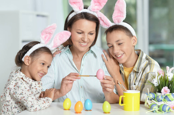 Mother with her son and daughter wearing bunny ears painting eggs for Easter - Foto, Imagem