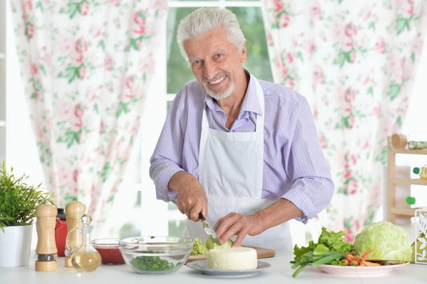Senior man  preparing dinner in kitchen - Foto, afbeelding