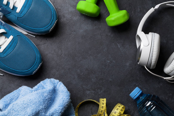 Fitness concept background with sneakers, headphones, dumbbells, water bottle and tape measure. Top view with space for your text - Fotoğraf, Görsel