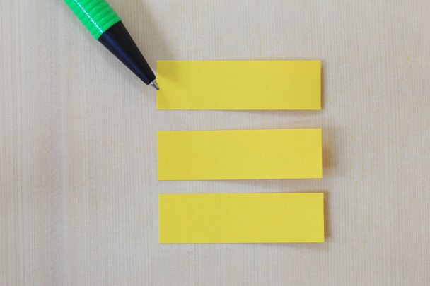 Zöld toll mutatva-hoz üres sárga papír jegyzék a fa padló-ba - Fotó, kép
