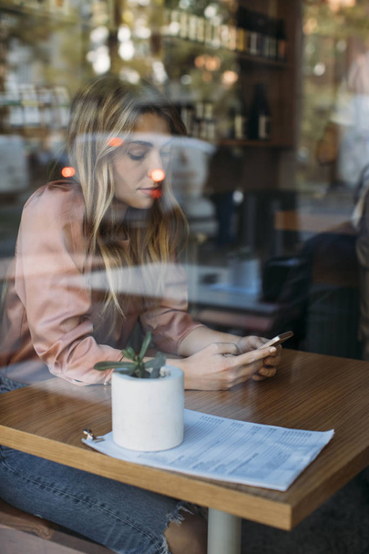 Mooie vrouw te typen op de mobiele telefoon bij koffie Shop - Foto, afbeelding