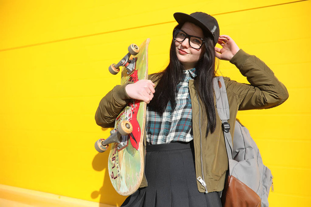 A young hipster girl is riding a skateboard. Girls girlfriends f - Zdjęcie, obraz