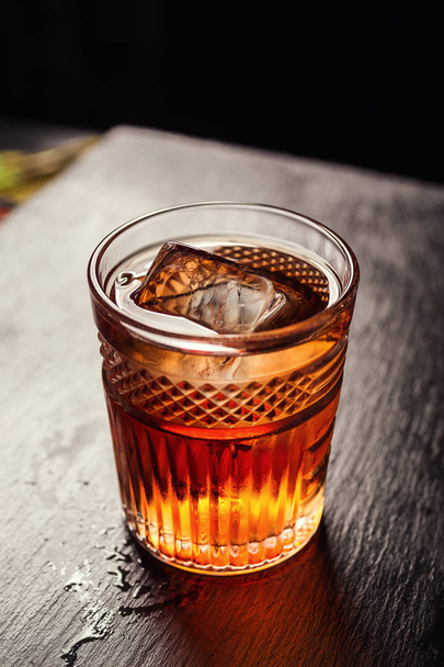 Glas Whisky (Cognac oder Brandy) mit Zitronen- und Eiswürfeln auf der Theke  - Foto, Bild