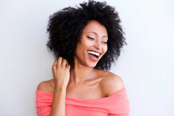Lähikuva muotokuva houkutteleva nuori musta nainen nauraa valkoista taustaa vasten
 - Valokuva, kuva