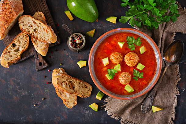 Spicy tomato soup with meatballs and vegetables. Served with avocado and parsley. Healthy dinner.Flat lay. Top view - Photo, Image