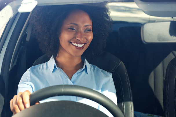 Porträt einer glücklichen jungen afrikanisch-amerikanischen Frau, die Auto fährt und lächelt - Foto, Bild