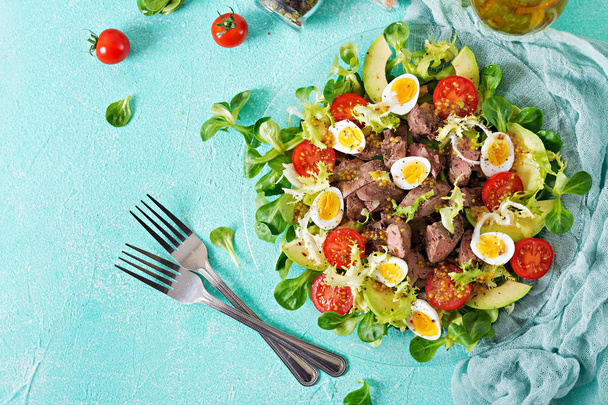 Warm salad from chicken liver, avocado, tomato and quail eggs. Healthy dinner. Dietary menu. Flat lay. Top view - Photo, Image