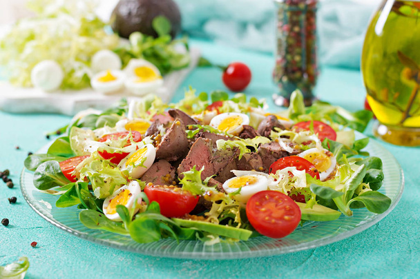 Warm salad from chicken liver, avocado, tomato and quail eggs. Healthy dinner. Dietary menu. - Photo, Image