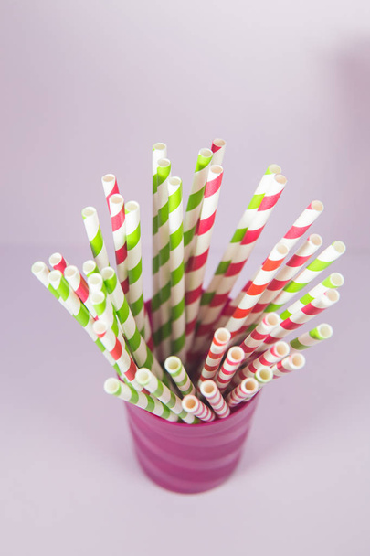 Multicolored straws in the plastic purple cup on the pink backgr - Foto, Imagem