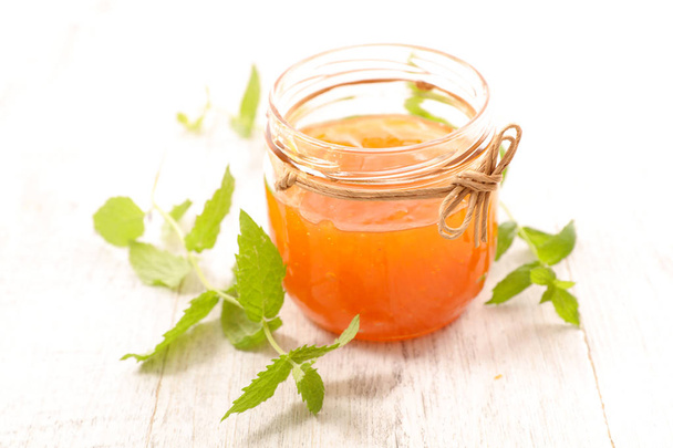  peach jam in jar with mint and fresh peach on light wooden background - Foto, afbeelding