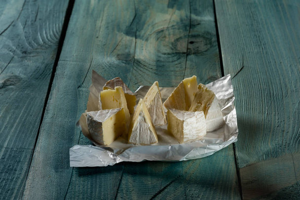 rustic flat lay with sliced camamber cheese on blue wooden background - Valokuva, kuva