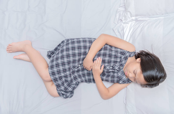 Asijská dívka trpící břicho na postel  - Fotografie, Obrázek
