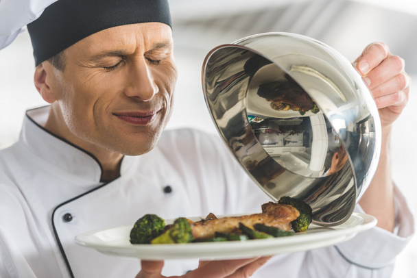 beau chef renifler plat au restaurant cuisine avec les yeux fermés
 - Photo, image