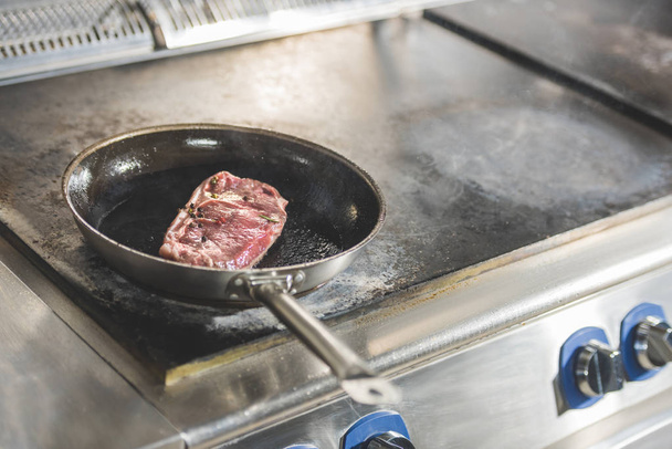 steak frying on frying pan at restaurant kitchen - Foto, afbeelding