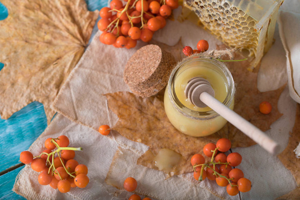 Ягоды роуэн, стакан с медом и сотовыми сотами на мешковине
. . - Фото, изображение