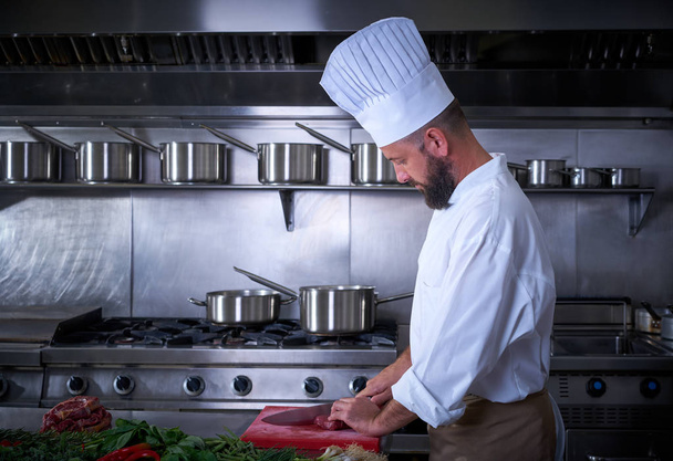Chef cutting meat in restaurant kitchen - Fotó, kép