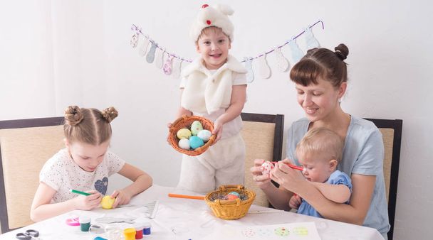 Family celebrates Easter: Mom and children paint Easter eggs at the table. - Fotó, kép