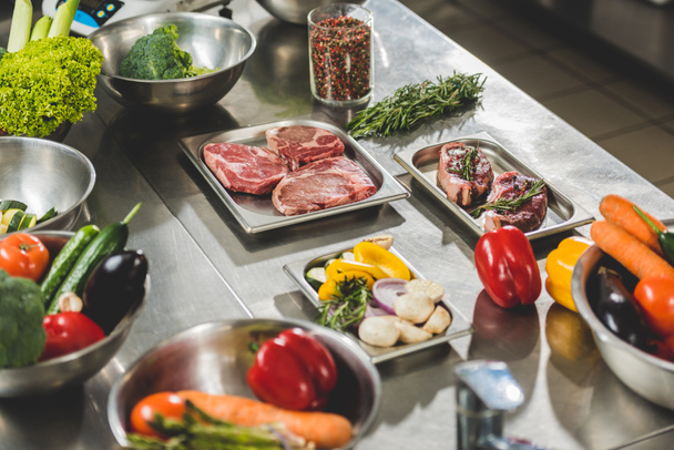 raw meat with vegetables on table in restaurant kitchen - 写真・画像