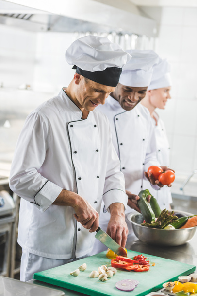 lachende multiculturele chef-koks bereiden van voedsel op restaurant keuken - Foto, afbeelding