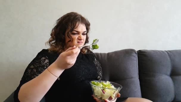 piękna dziewczyna jedzeniu sałatkę na kanapie emocji - Materiał filmowy, wideo