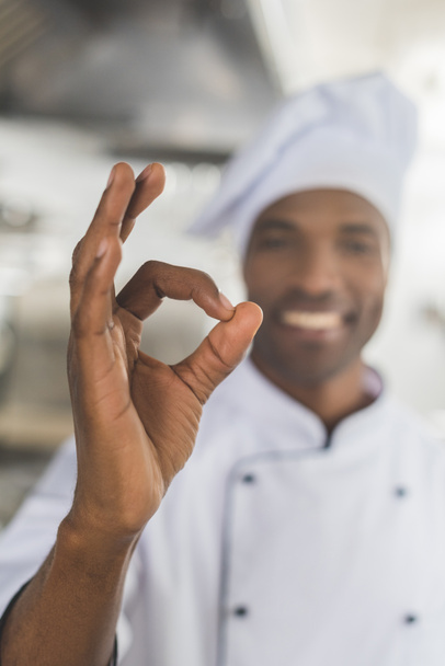 Симпатичный африканский американский шеф-повар показал хороший жест на кухне ресторана.
 - Фото, изображение