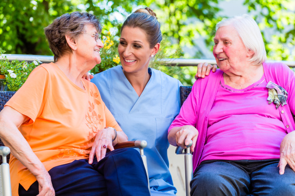 Infirmière gériatrique discutant avec des femmes âgées dans une maison de retraite
 - Photo, image