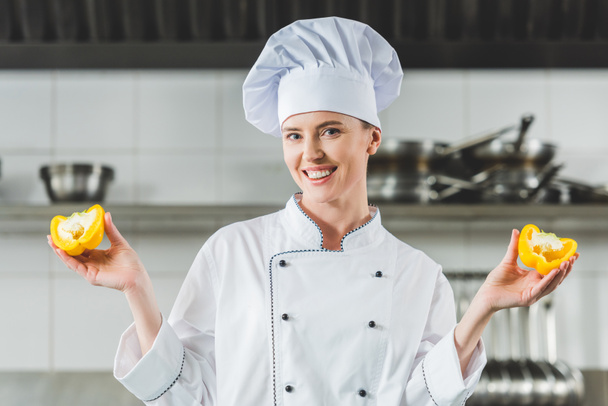 chef atraente mostrando metades de pimentão na cozinha do restaurante
 - Foto, Imagem