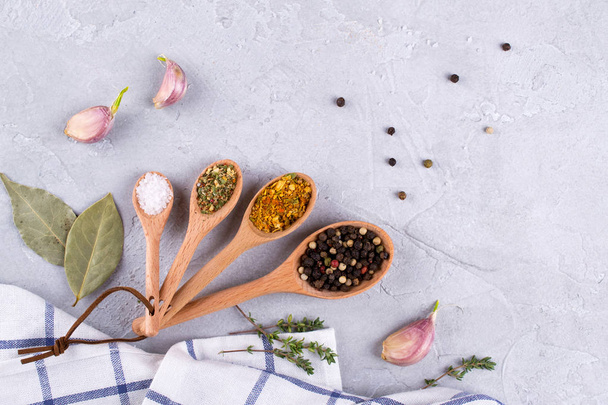 Wooden spoons with spices and herbs on textured gray background. Food flat lay. - Fotoğraf, Görsel