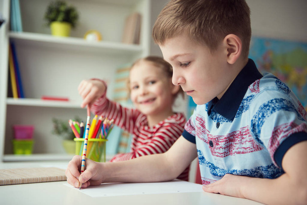 Two cute children drawing with colorful pencils  - Fotó, kép