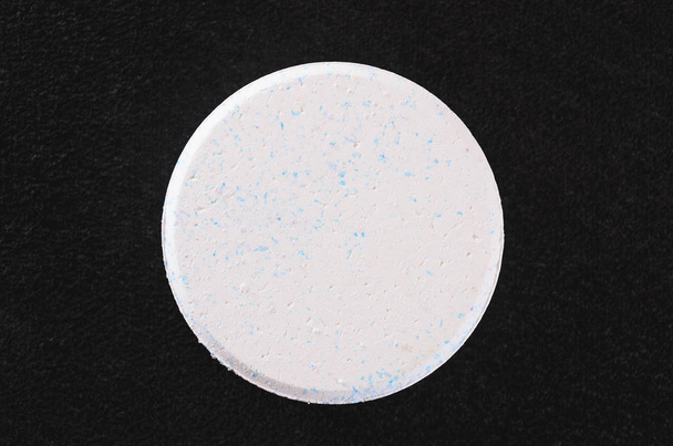 Comprimé blanc de chlore arrondi isolé sur un backgr foncé texturé
 - Photo, image