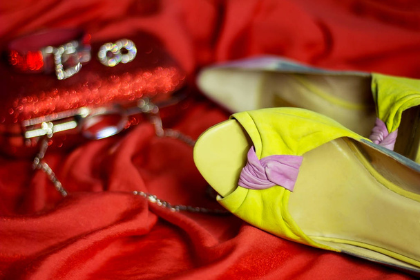 mooie glanzende accessoires en schoenen met hoge hakken en een rode koppeling op de avondjurk - Foto, afbeelding