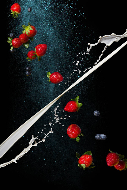 Γάλα και φράουλα σε σκούρο φόντο. Σταματήστε τη στιγμή σε συνθήκες μηδενικής βαρύτητας - Φωτογραφία, εικόνα