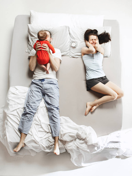 Top view of happy family with one newborn child in bedroom. - Фото, изображение