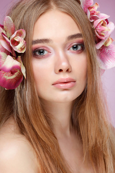 Beautiful girl, isolated on a light - violet  background with varicoloured flowers in hairs, emotions, cosmetics - Photo, image