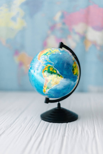 Globe on a wooden white table on the background of a world map. - Фото, зображення