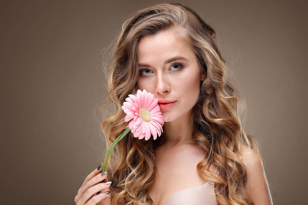 Beautiful girl, isolated on a light - grey background with varicoloured flowers in hairs, emotions, cosmetics - Photo, image