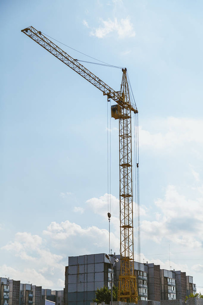 Lifting tower crane against cloudy sky background - Foto, afbeelding