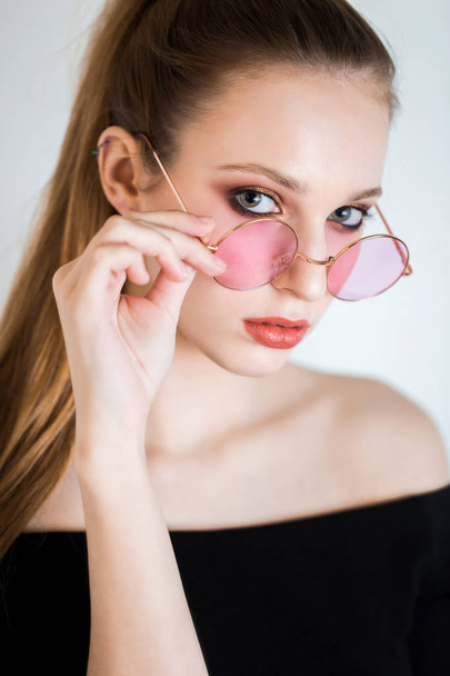 Sexy blonde woman in pink glasses on white background. Beautiful girl with professional makeup looking at the camera - Foto, Imagen