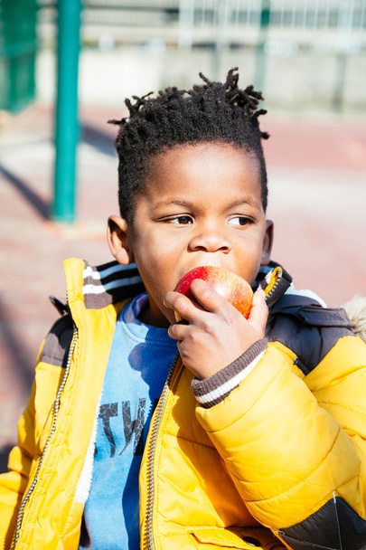 Мальчик ест яблоко на открытом воздухе
 - Фото, изображение