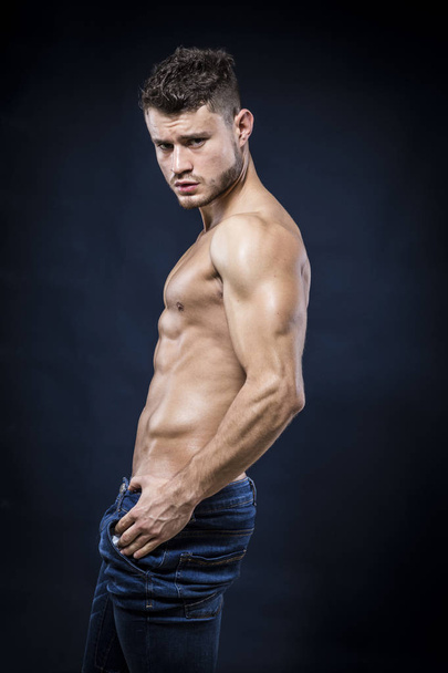 Young strong man on dark background - Foto, afbeelding