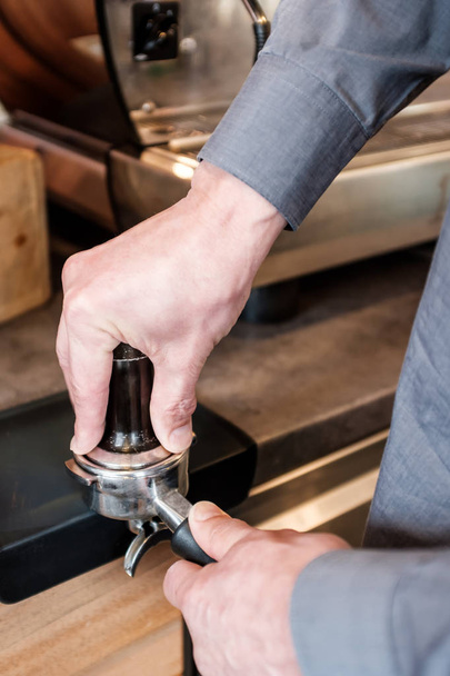 Barista presionando café con tamper en portafilter para hacer espresso
 - Foto, Imagen
