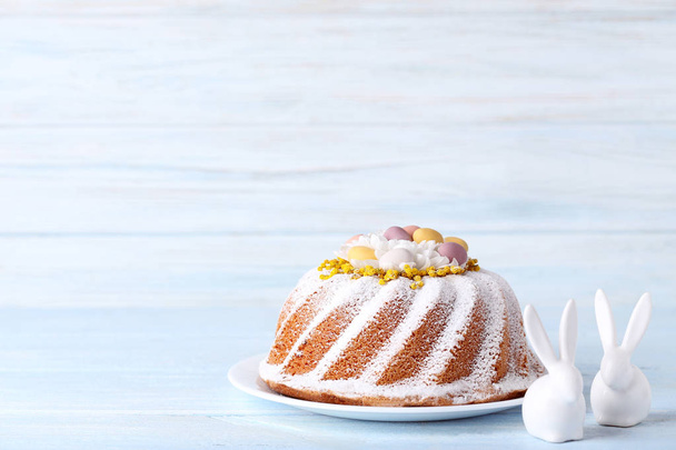 Вкусный пасхальный торт с керамическими кроликами на деревянном столе
 - Фото, изображение