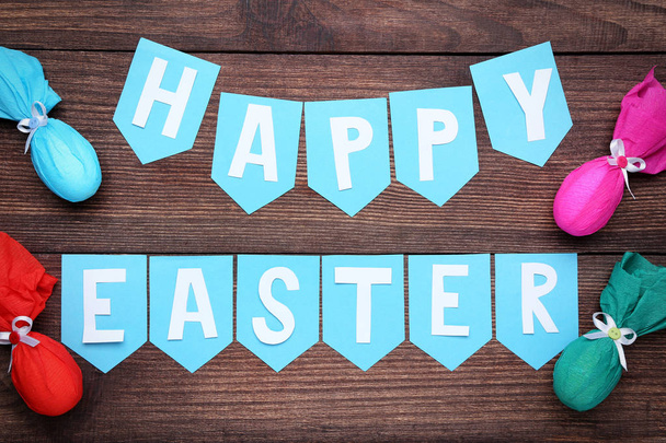 Veselé Velikonoce nápis s vejci na hnědý dřevěný stůl - Fotografie, Obrázek