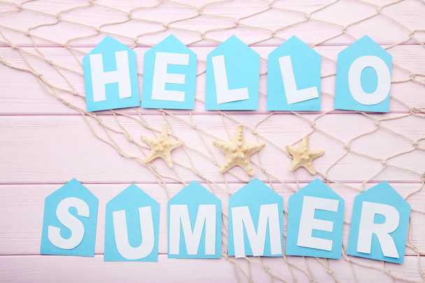 Inscription Hello Summer with starfishes and fishing net on wooden background - Foto, afbeelding