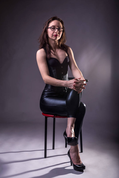 Sexy young woman in a corset and latex on a chair. - Foto, imagen