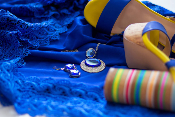      sandalias de mujer con tacón alto en el fondo de azul vestido de noche azul con accesorios brillantes
 - Foto, Imagen