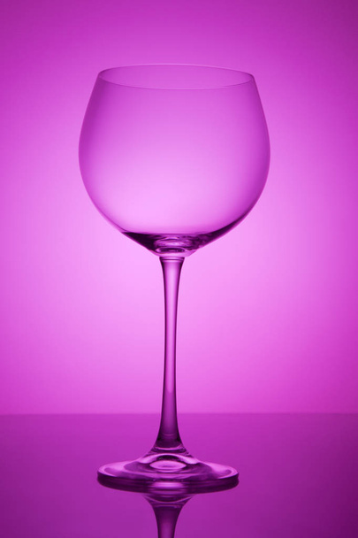 Wijnglas leeg op kleurrijke abstracte achtergrond. - Foto, afbeelding
